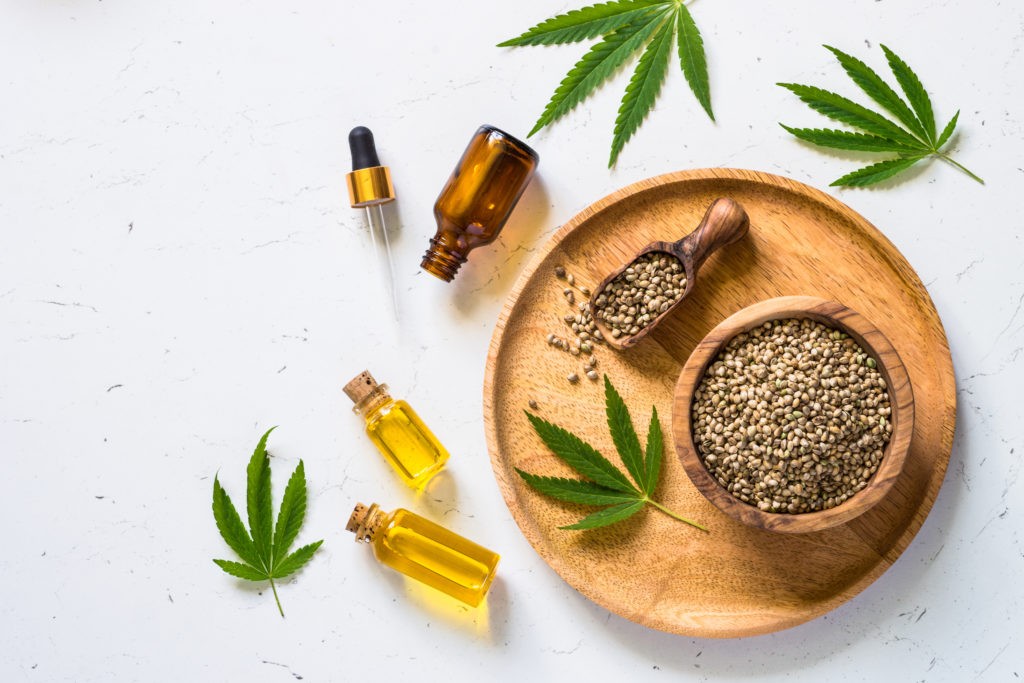 Cannabis oil hemp oil with cannabis seeds and cannabis leaves at white table. Top view with copy space.